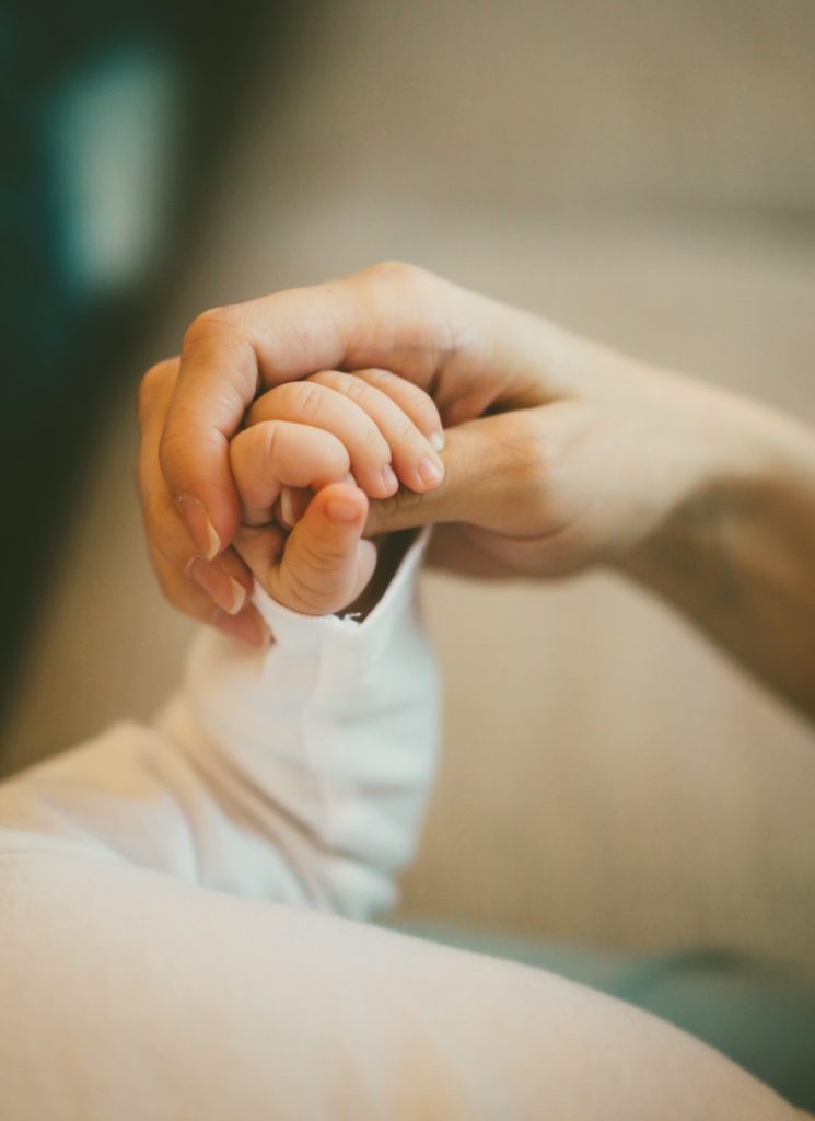 Adult hand holding a baby's hand