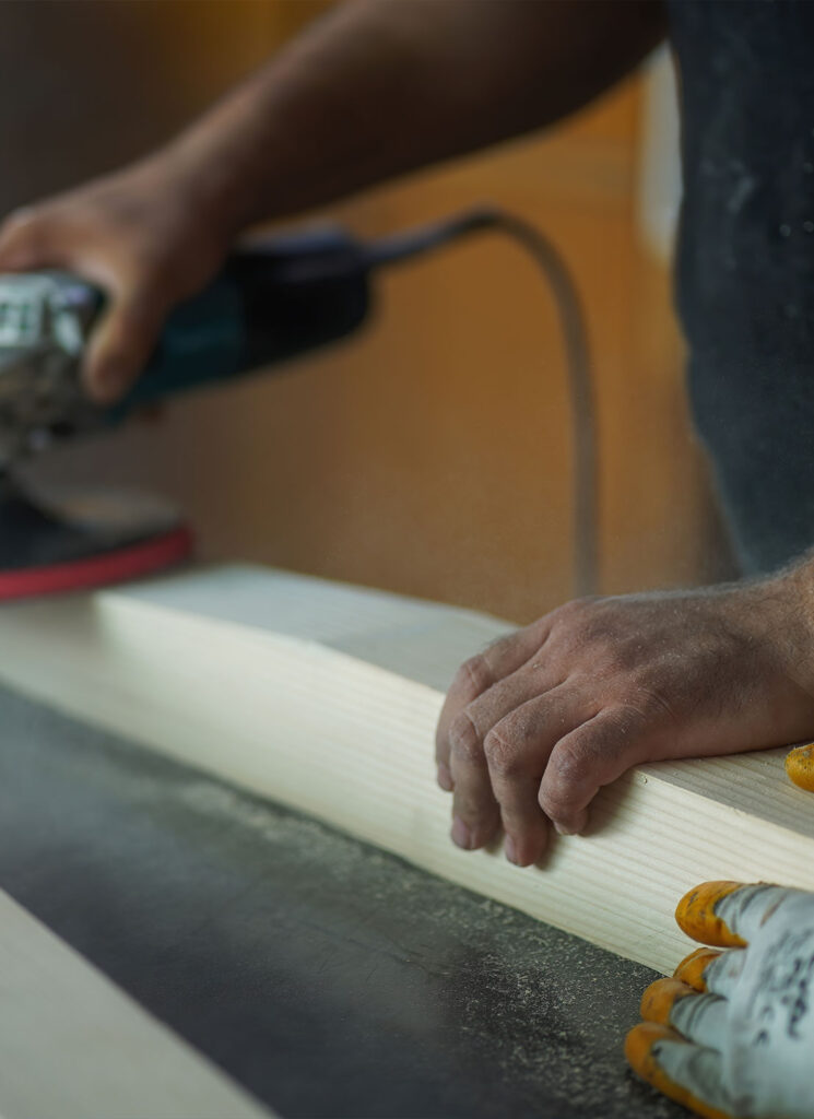 Carpenter's hands sanding a piece of wood